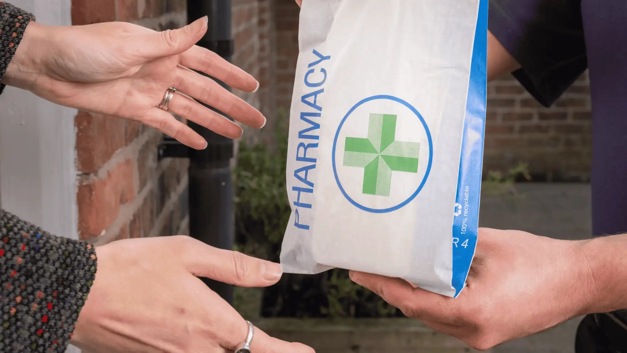 White paper pharmacy bag with green cross logo and blue trim